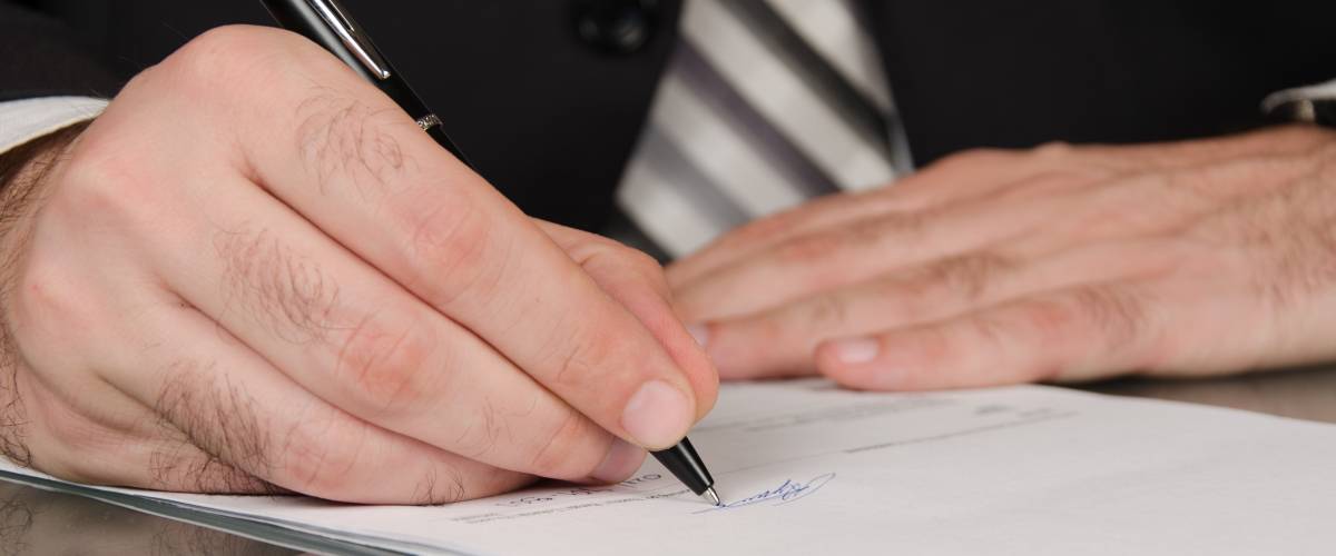 Businessman in a suit, signing legal document