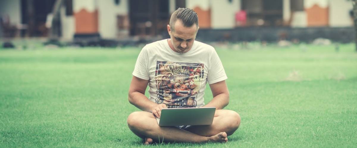 Man using laptop computer outdoors on grass