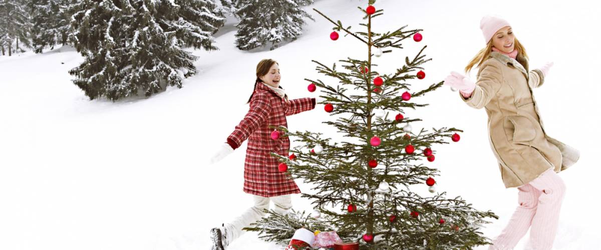 Two girls dancing around Christmas tree