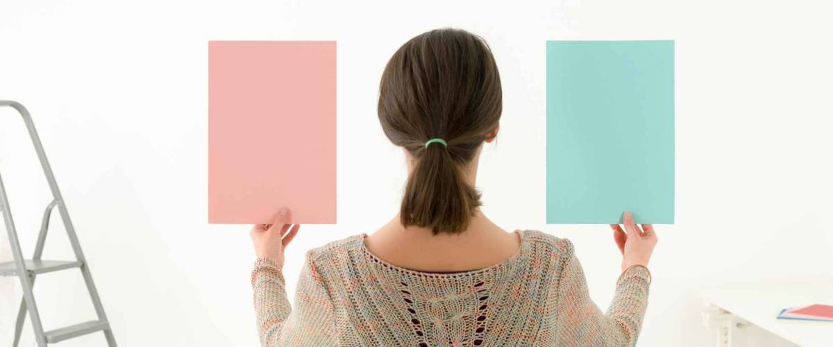 Rear view of a woman choosing colour for painting a room against white background