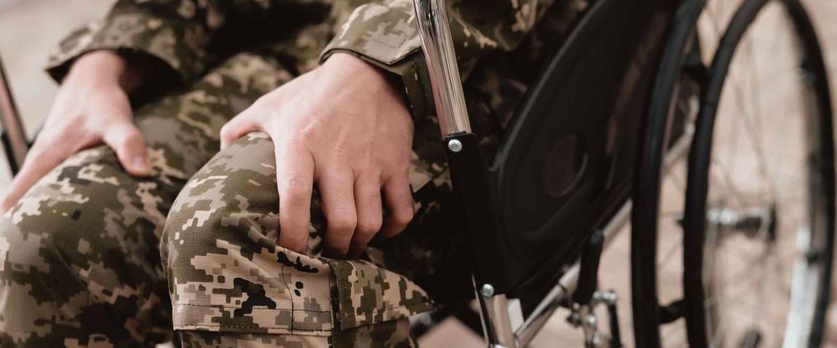 Veteran in wheelchair returned from army. Close-up photo veteran in a wheelchair. Wheelchairs and legs in military uniform.
