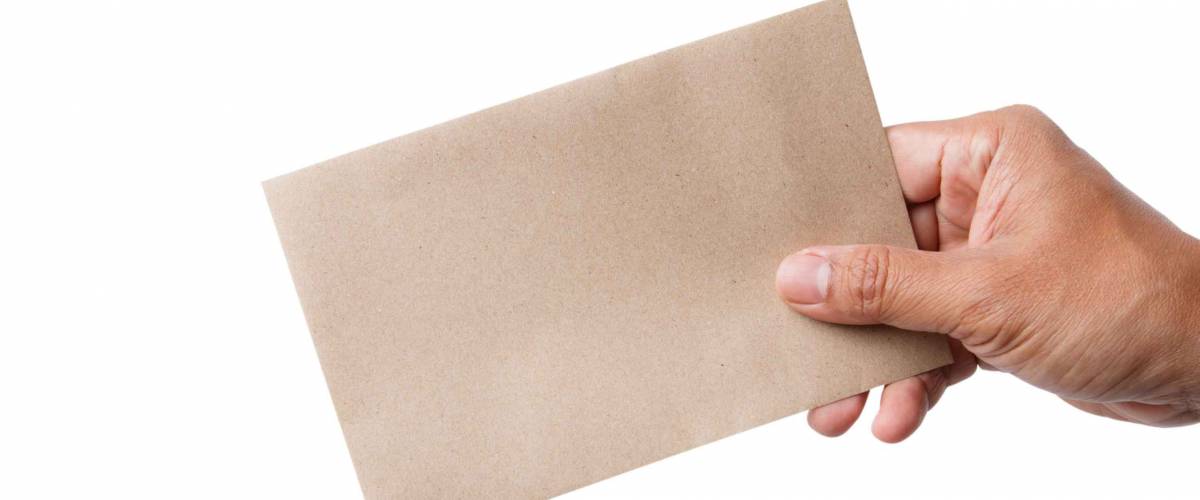 The man's hand sends a brown envelope isolated on white background. It represents the symbol of human communication before being replaced by a smartphone.