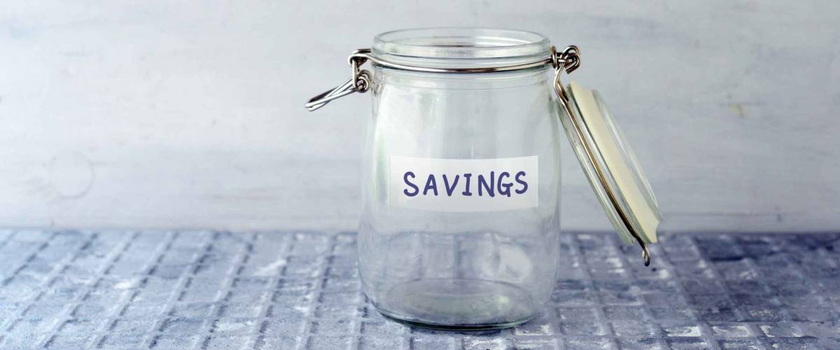Empty glass money jar with savings label, financial concept.
