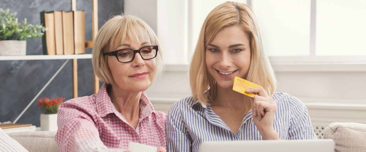 Adult woman and daughter shopping online with credit card and laptop