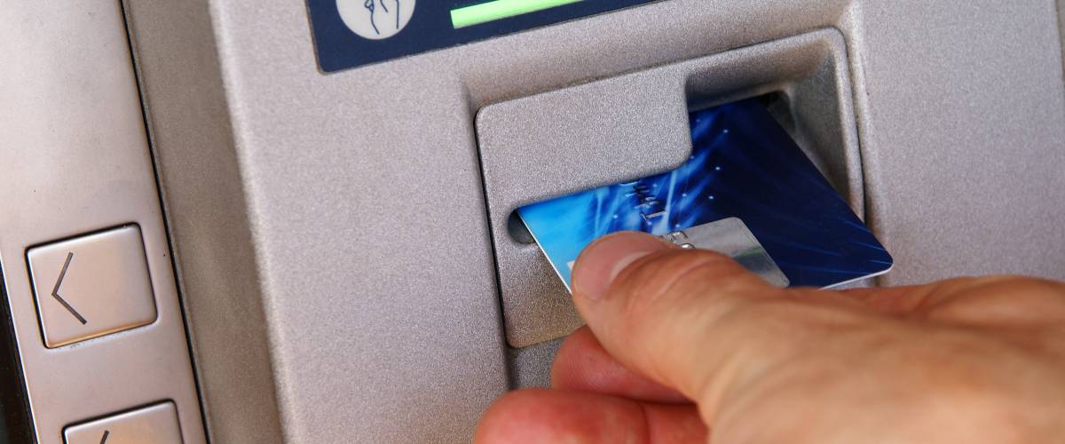 Bank customer inserting a bank card into an ATM