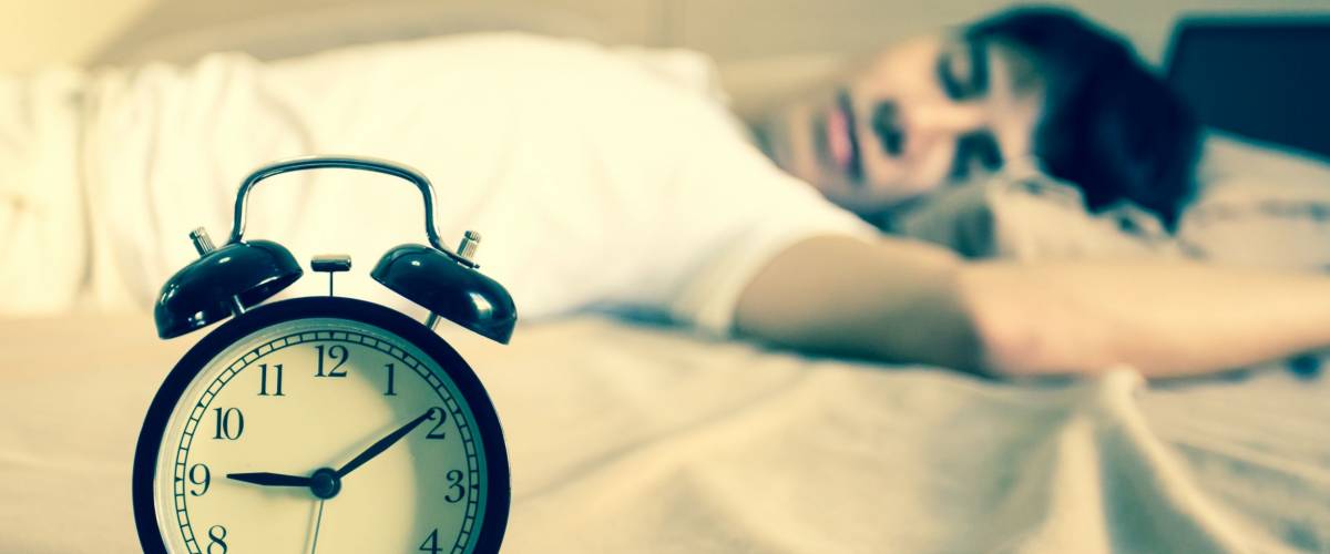 Man sleeping with alarm clock on morning.