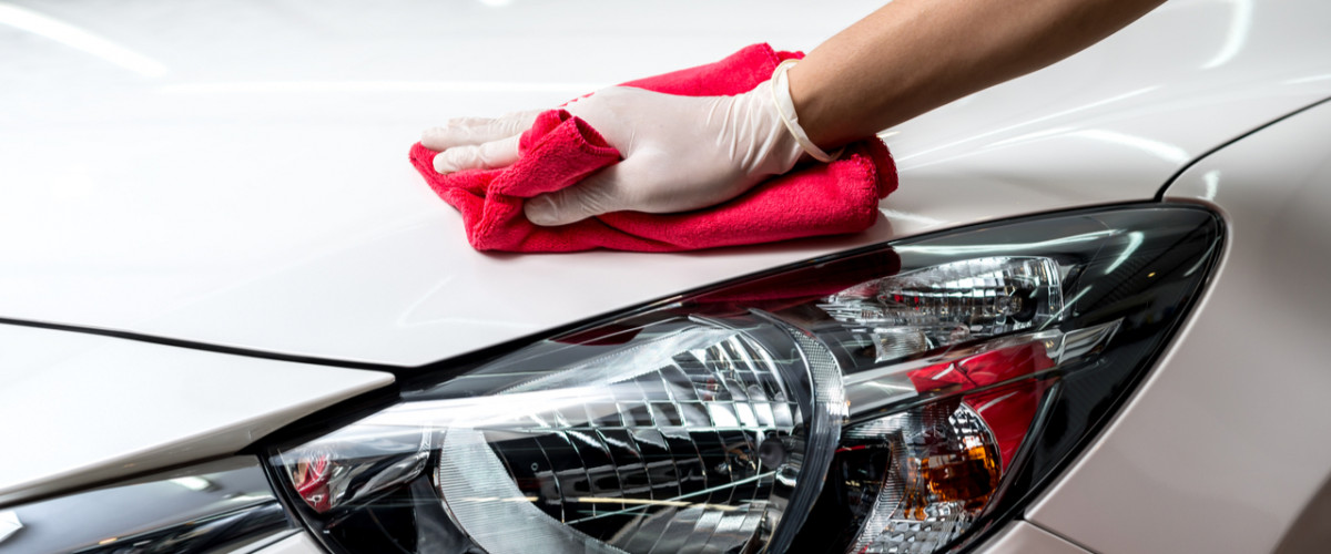 Car detailing cleaning a white car with a microfibre cloth and a white glove