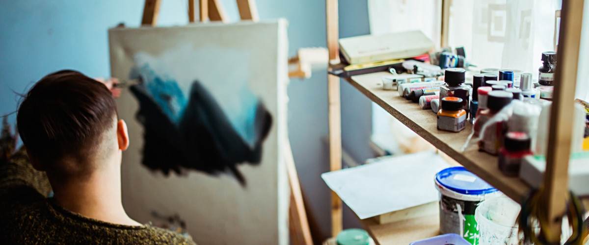 Male artist working on a painting in his home studio