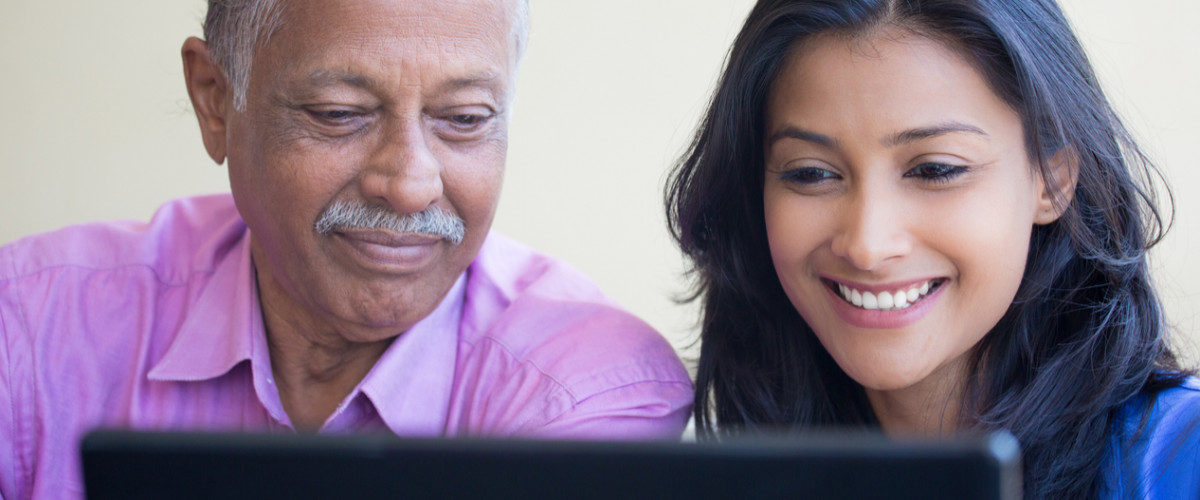 Closeup portrait, sitting young woman showing elderly man to use black laptop, happy at what they see , isolated indoors background