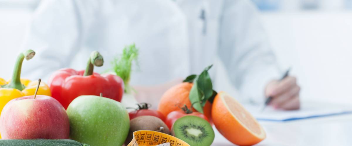 Nutritionist desk with healthy fruit, vegetables and a measuring tape, weight loss and diet concept