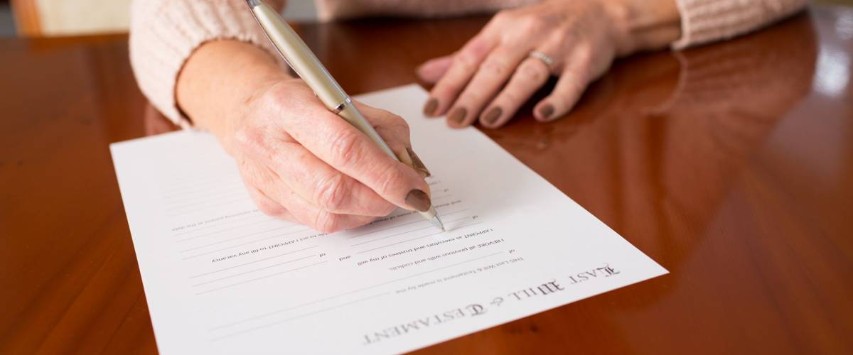 Senior Woman Signing Last Will And Testament At Home