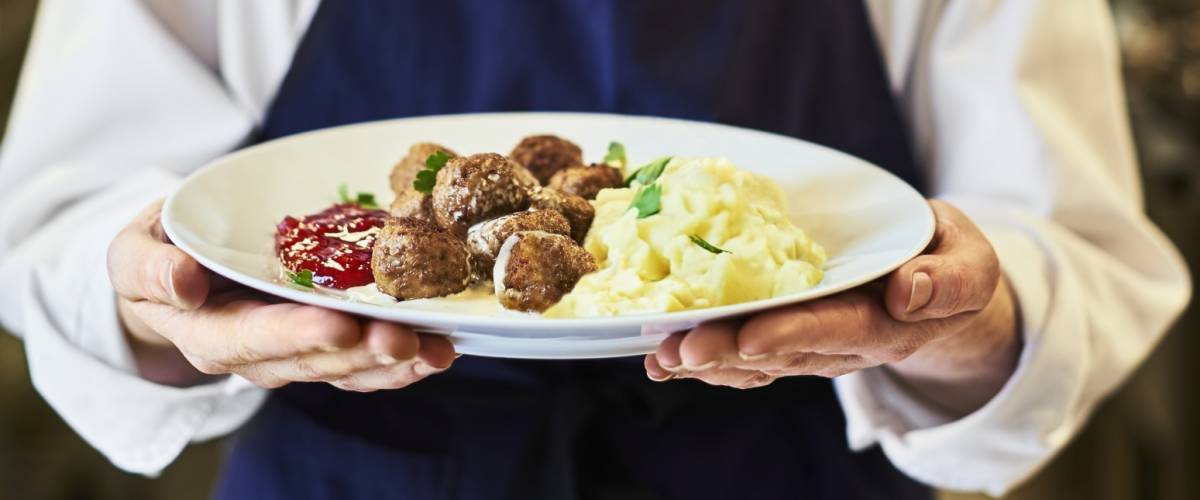 Restaurant worker holding a plate of chicken meatballs