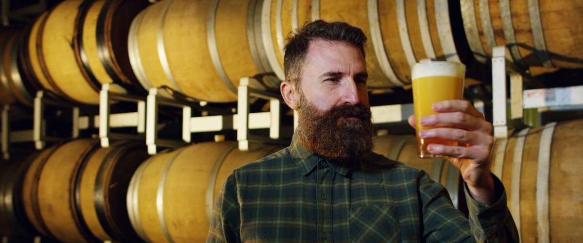 a brewmaster expert checks the quality of the freshly tapped beer from wooden barrels formerly used for flavour the wine or beer.