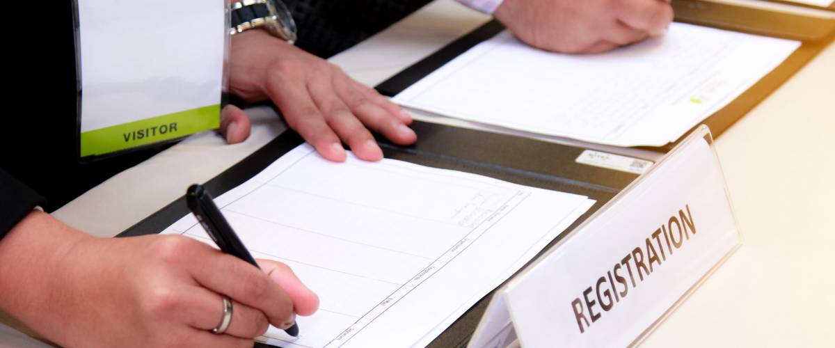close-up of registration desk in front of conference center with Businessman Writing on the Table