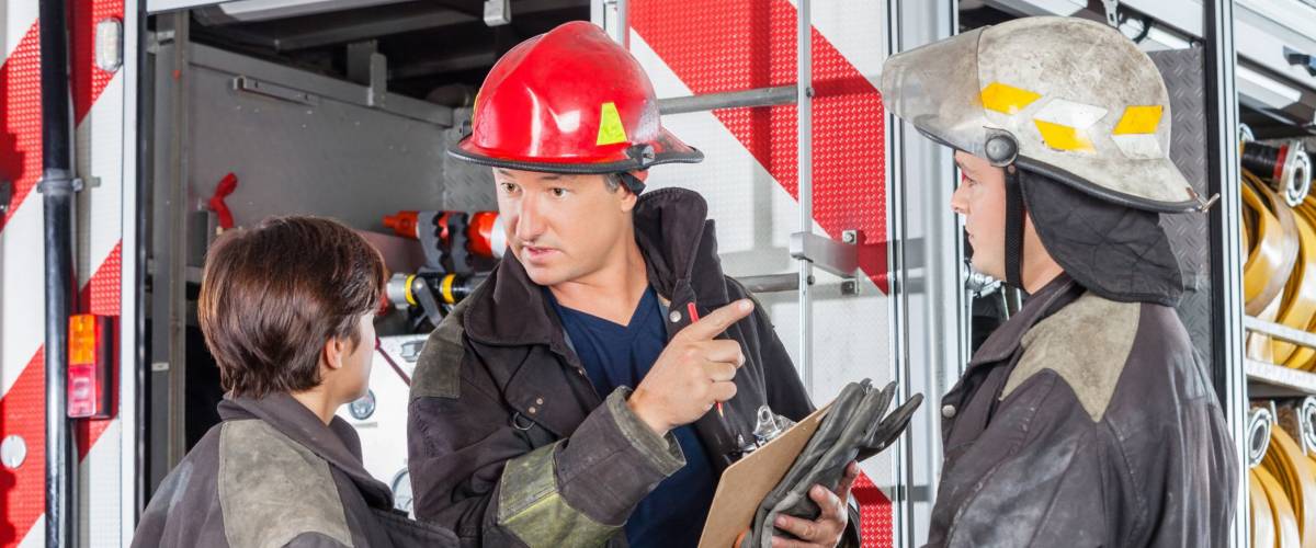 Firefighter Discussing With Colleagues At Fire Station