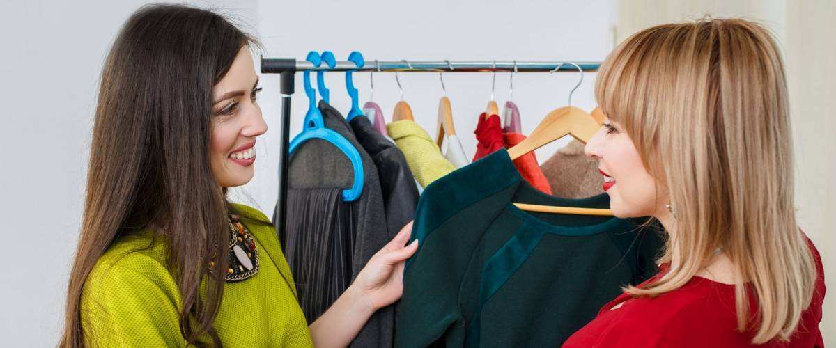girl with stylist choosing her fashion outfit. Women deciding what to wear. Analysis of the client's wardrobe. Fashion stylist consultation. Master class about how to stylishly clothing