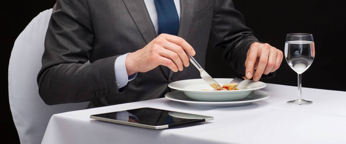 restaurant, people, technology and holiday concept - smiling man with tablet pc eating main course at restaurant