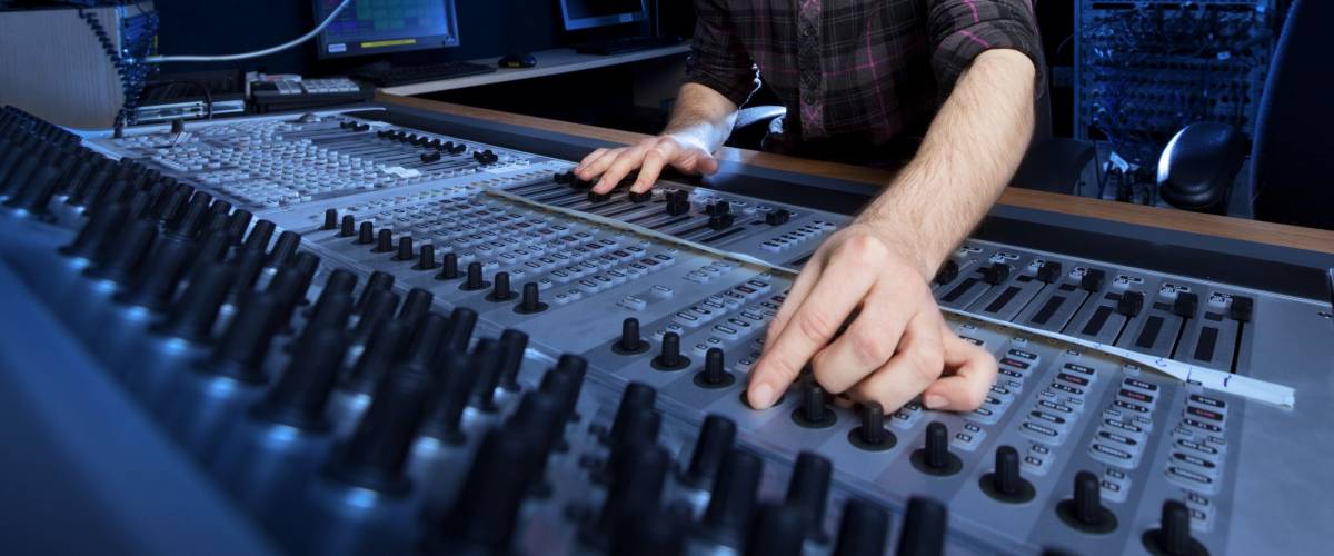 Man using a sound mixing desk in a recording studio.