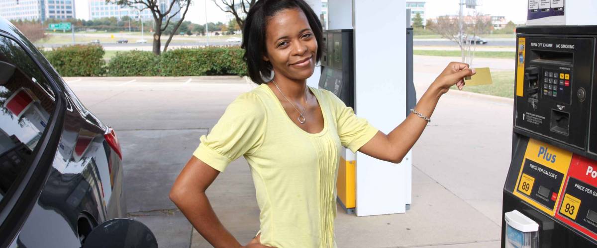 Pretty woman at gas station using credit card paying for gas