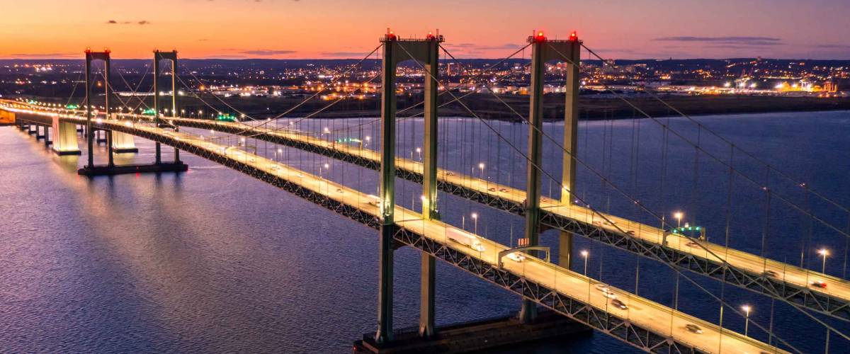 Aerial view of Delaware Memorial Bridge at dusk. The Delaware Memorial Bridge is a set of twin suspension bridges crossing the Delaware River between the states of Delaware and New Jersey