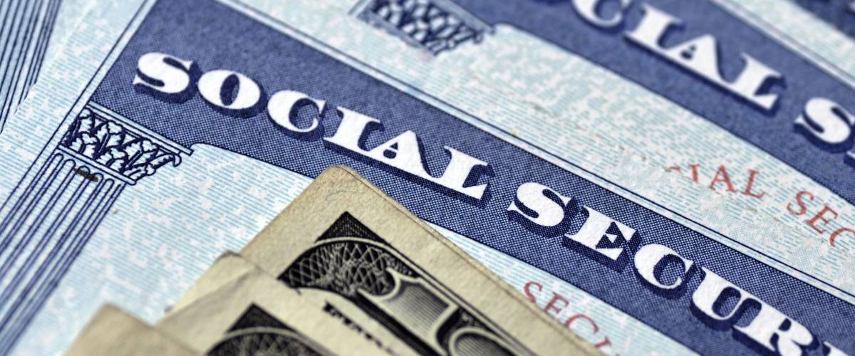 Detail of several Social Security Cards and cash money symbolizing retirement pensions financial safety
