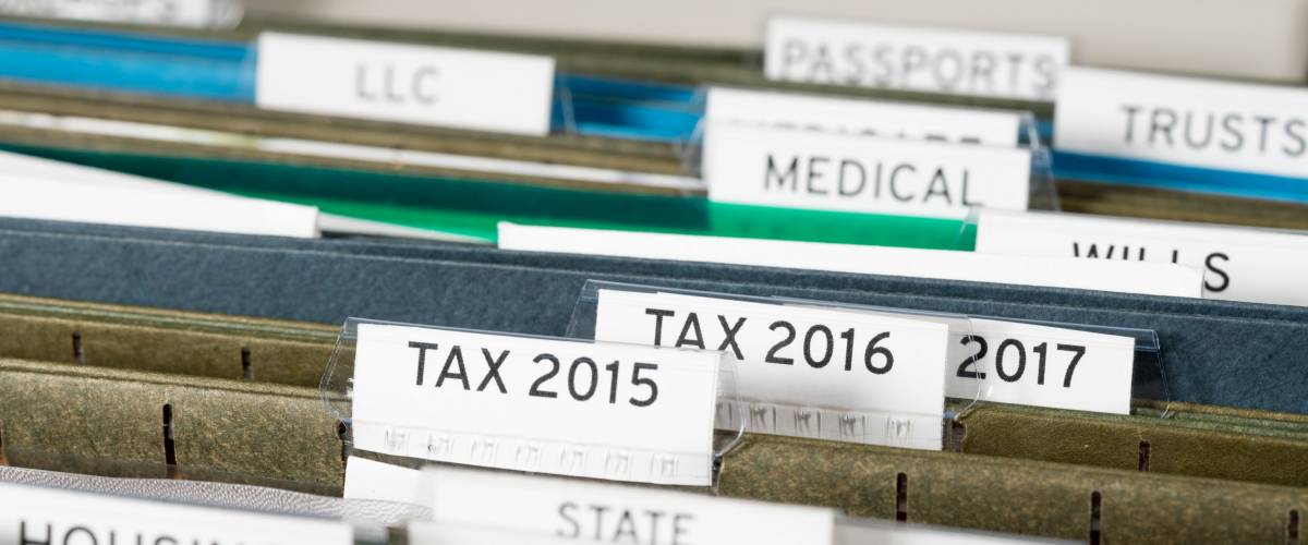 Close up of a well organized home filing system with tabs for each subject and focus on tax return papers