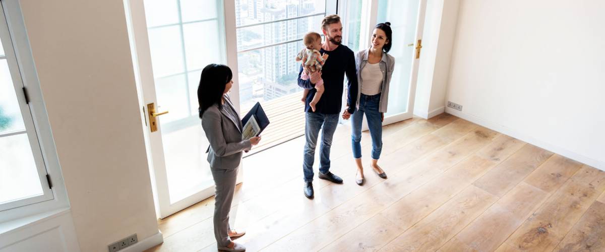 An agent shows a young family a house for sale.