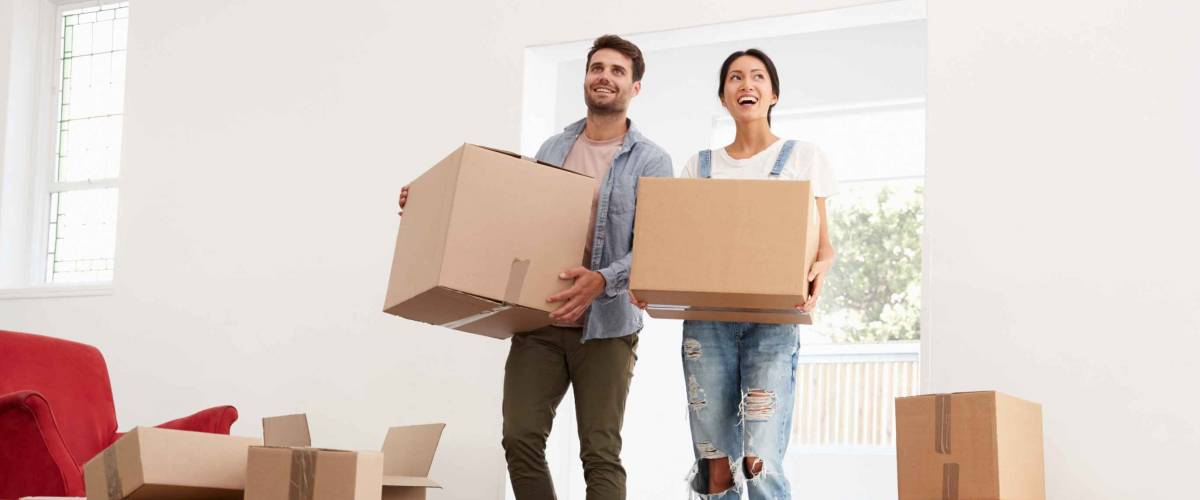 Couple Carrying Boxes Into New Home On Moving Day