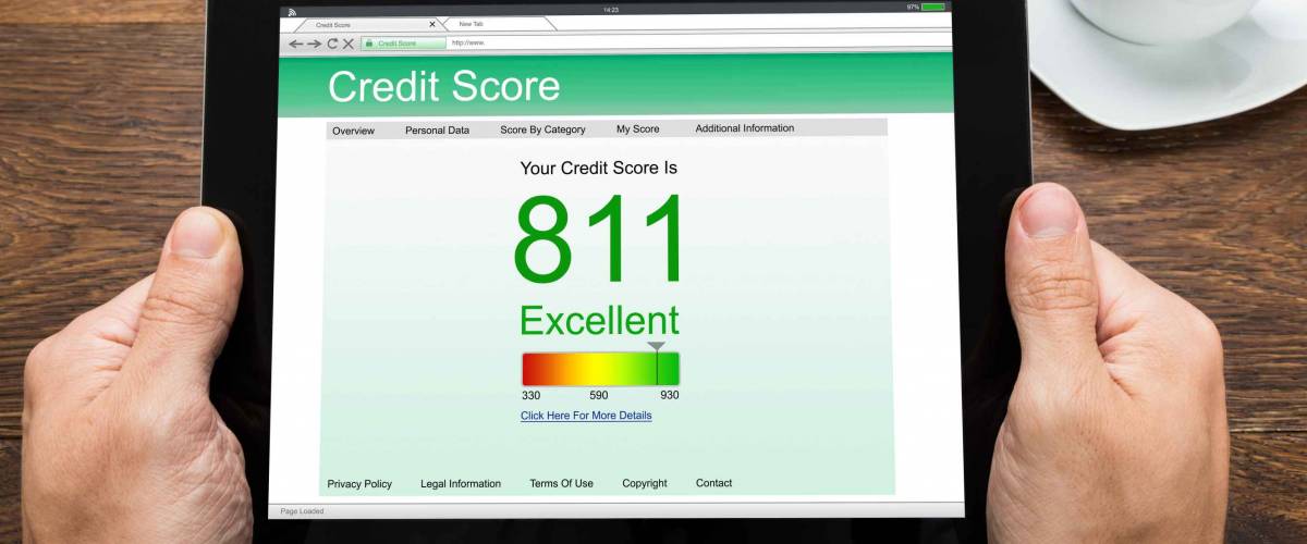 Close-up Of Person Hands With Digital Tablet Showing Credit Score At Desk