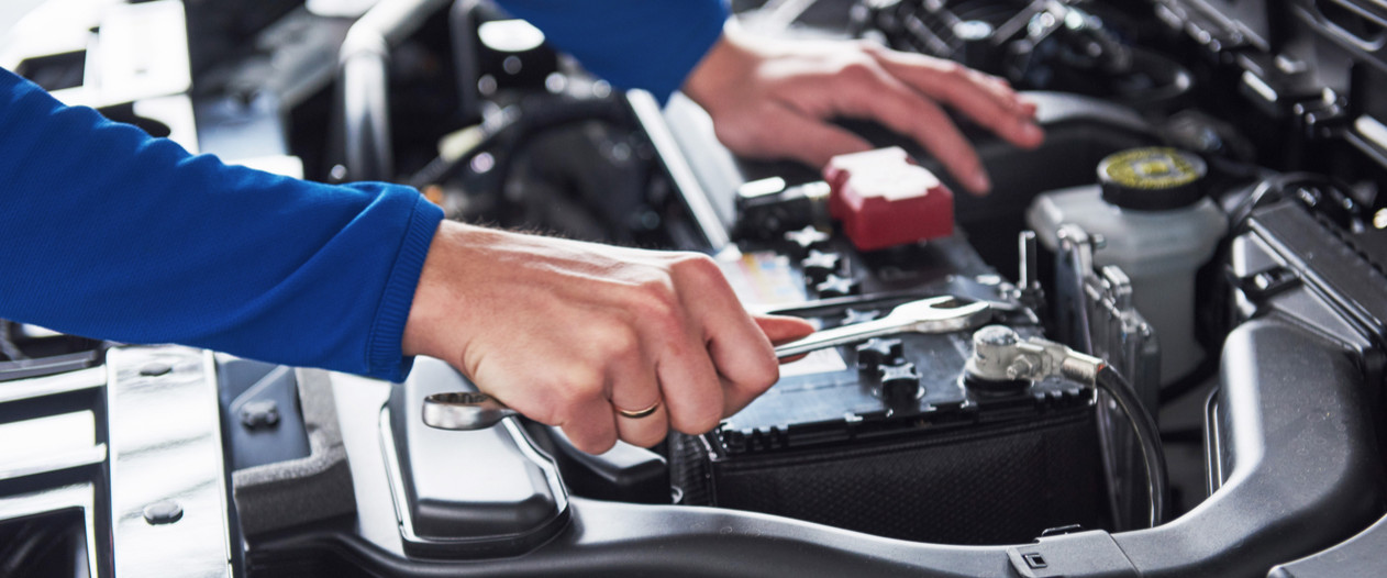 Hands of car mechanic with wrench in garage