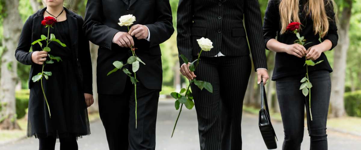 Torso of family on cemetery mourning holding red and white roses in hands