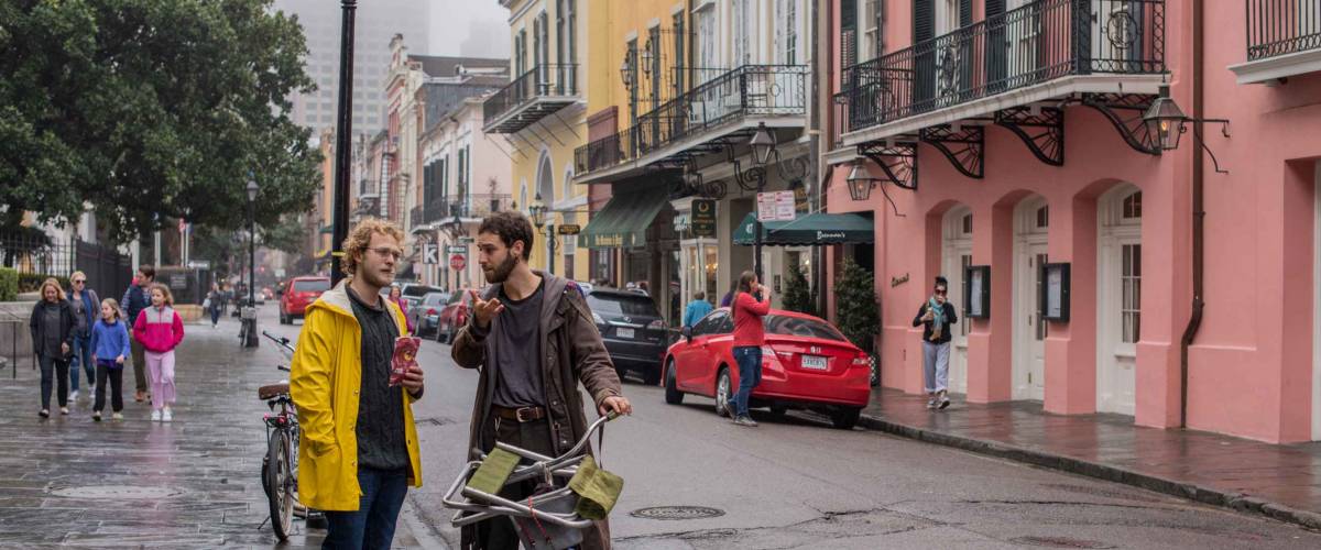 New Orleans, LA/USA - Jan. 28, 2018: Two friends hang out and talk on the sidewalk on Royal Street in the French Quarter on a rainy, winter day.