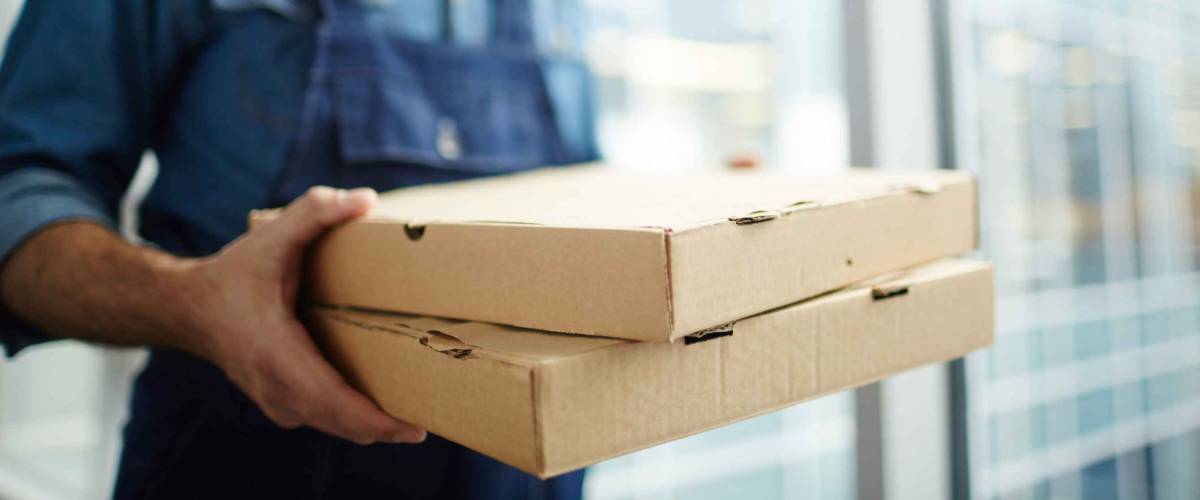 Two boxes with fast food being carried by delivery man in uniform for one of clients