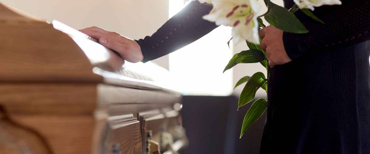 woman with white lily flowers and coffin at funeral in church