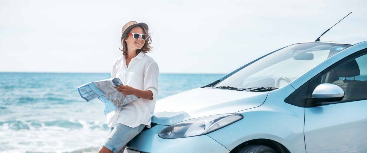 Beautiful stylish young girl travels by car, with a hat and with a card in her hands, summer travel, freedom, transport for rent, new impressions and adventure, freedom and youth