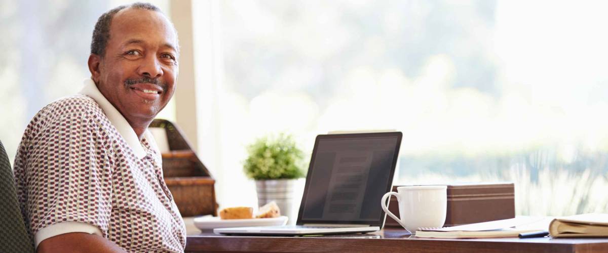 Senior Man Using Laptop On Desk At Home
