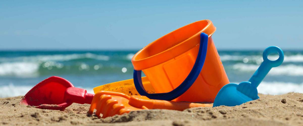 Children's beach toys - buckets, spade and shovel on sand on a sunny day