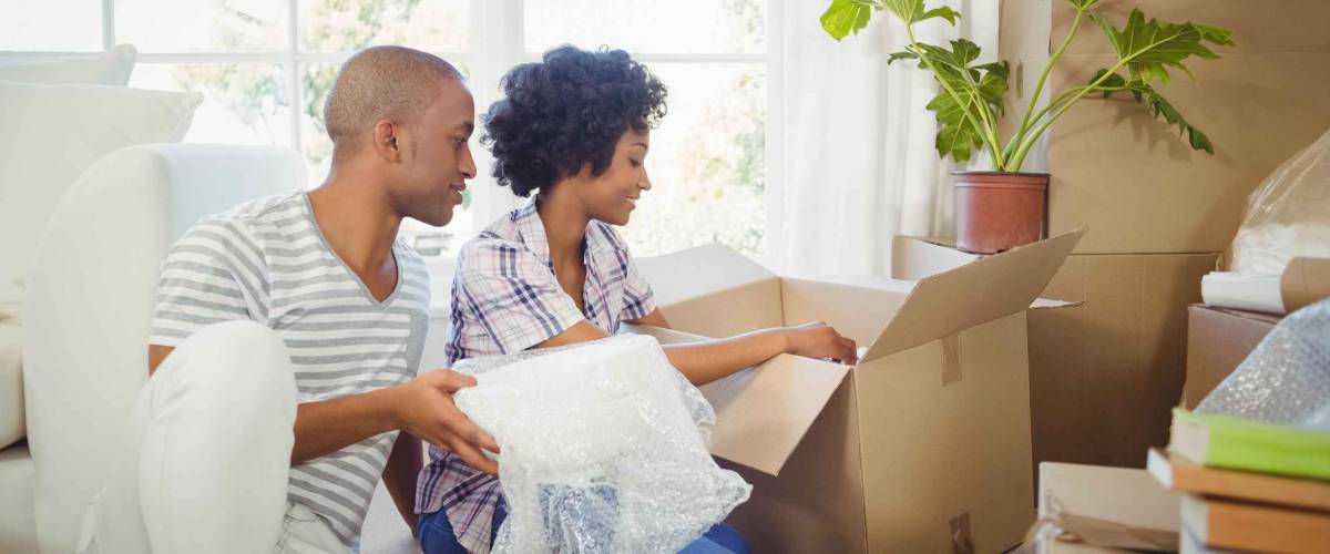 Happy couple opening boxes in the living room