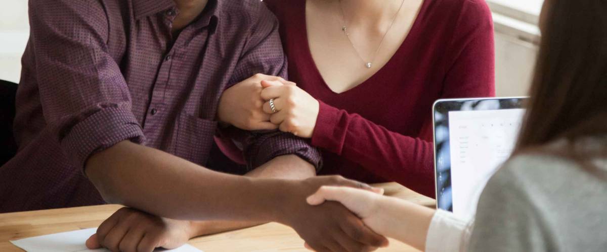 Smiling couple shaking hands with financial advisor