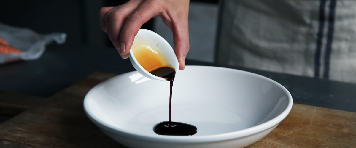 Pouring balsamic vinegar into a white dish